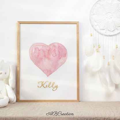 Affiche personnalisé avec un cœur rose pastel et un prénom écrit en or. 